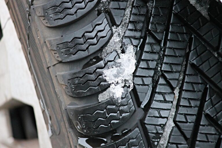 Nahaufnahme eines Winterreifens mit Lamellenprofil, in dessen Rillen Schneematsch haftet
